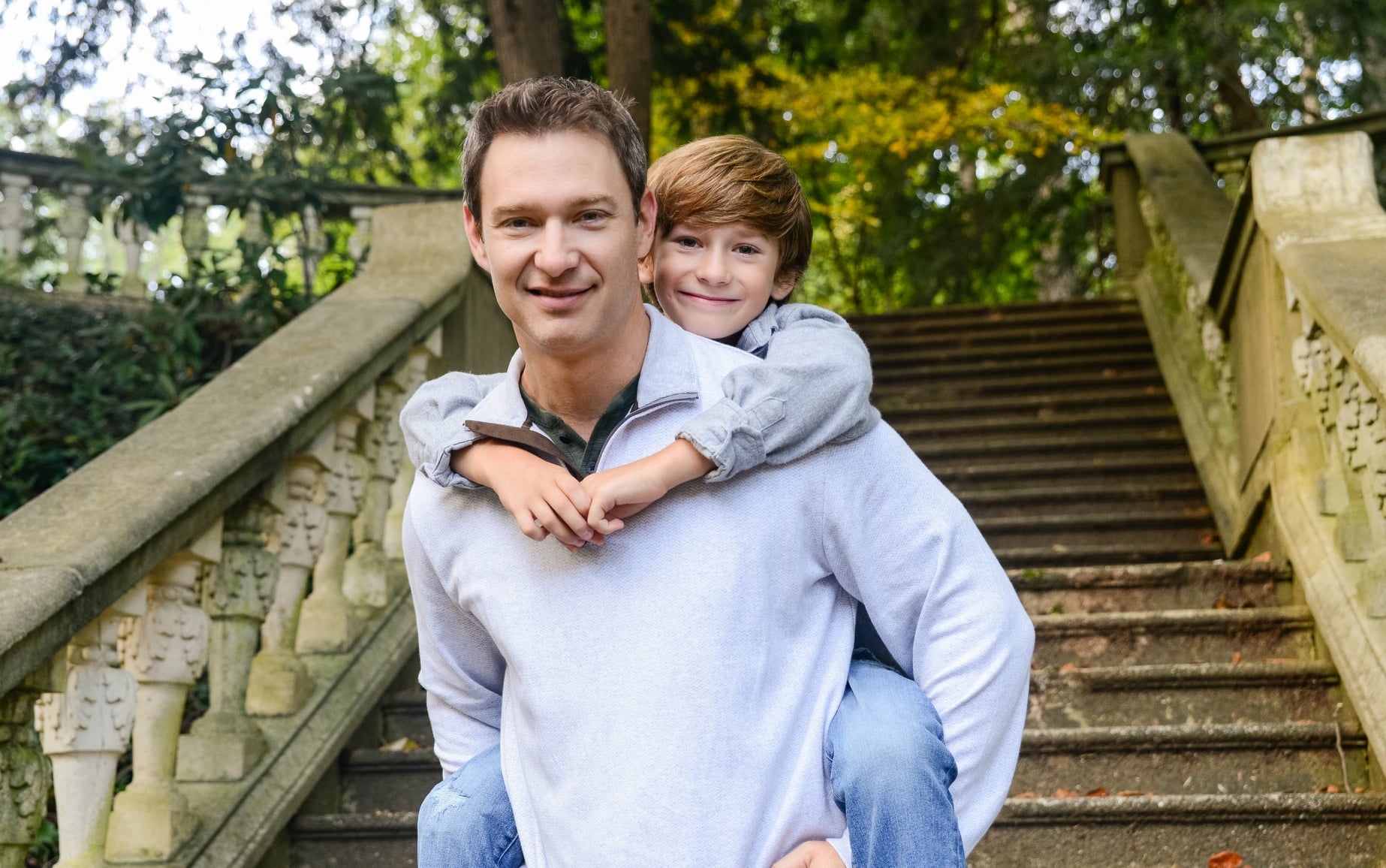 smiling man carrying a young boy piggy back