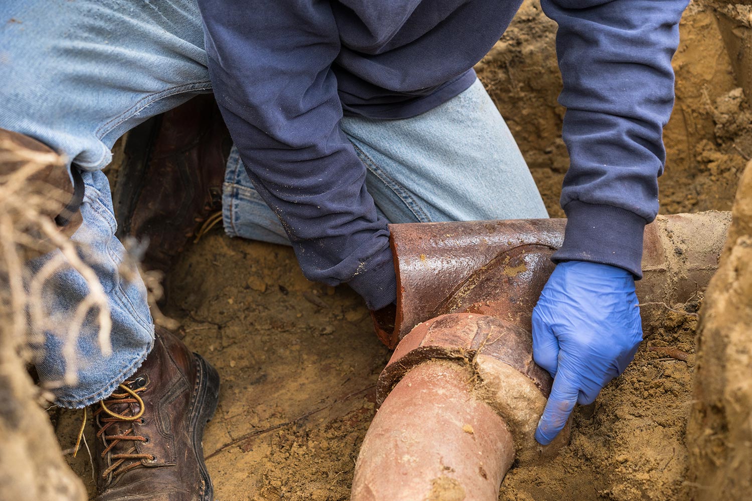 exposed sewage pipe with plumber's hand inside