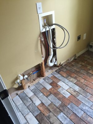 laundry room after water damage with brick floor being installed - during renovation