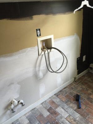 laundry room with brick floor installed, drywall replaced and partially painted