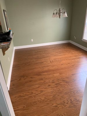 medium brown, wood floor in dining room with green walls & white trim