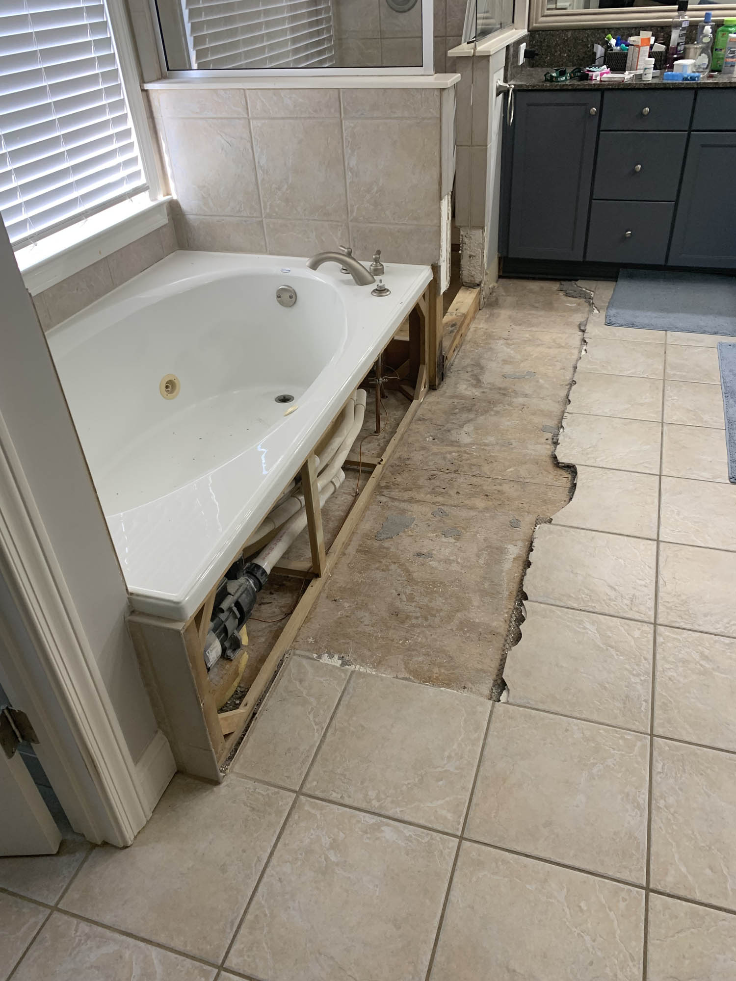 tub & shower area with wood floor exposed in bathroom before remodeling has begun